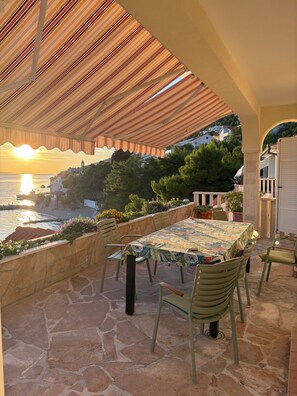 An outdoor patio with a table and chairs, overlooking a coastal area with a sunset view. - Enjoy Your Front Row Villa On The Adriatic Sea (Pisak)