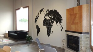 A modern waiting area with a world map mural, a fireplace, and comfortable seating.