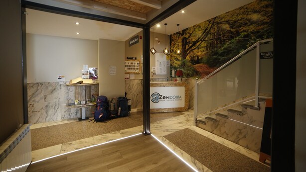 A reception area with a marble floor, a reception desk, and a staircase leading to an upper level.