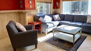 A living room with a grey sofa, a wooden coffee table, and a red accent wall. - Weekly Discount available! 4 Bedroom, 2 Bathroom, Walking Distance To Town (Southwest Harbor)