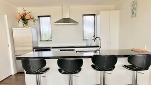 A modern kitchen with a central island, stainless steel appliances, and black bar stools.