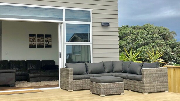 A modern house with a large sliding glass door leading to an outdoor patio area.