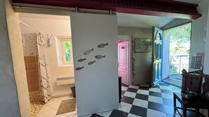 A room with a checkered floor, a white door with fish decals, a pink door, and a window with a view of greenery.