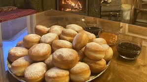Une pièce chaleureuse avec une cheminée, des murs en bois et une table sur laquelle est disposée une assiette de pâtisseries.