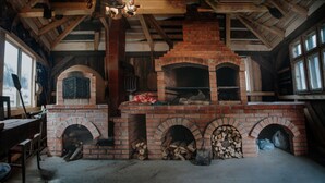 Une cheminée en briques rustique, dotée de plusieurs foyers, de poutres en bois et d’une cheminée.