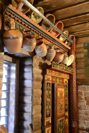 A wooden interior with a decorative shelf holding various pottery items. - Gospodaria Lui Nea Ion (Vama Buzaului)