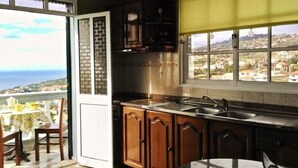 A kitchen with wooden cabinets, a stainless steel sink, and a view of the sea through a large window.