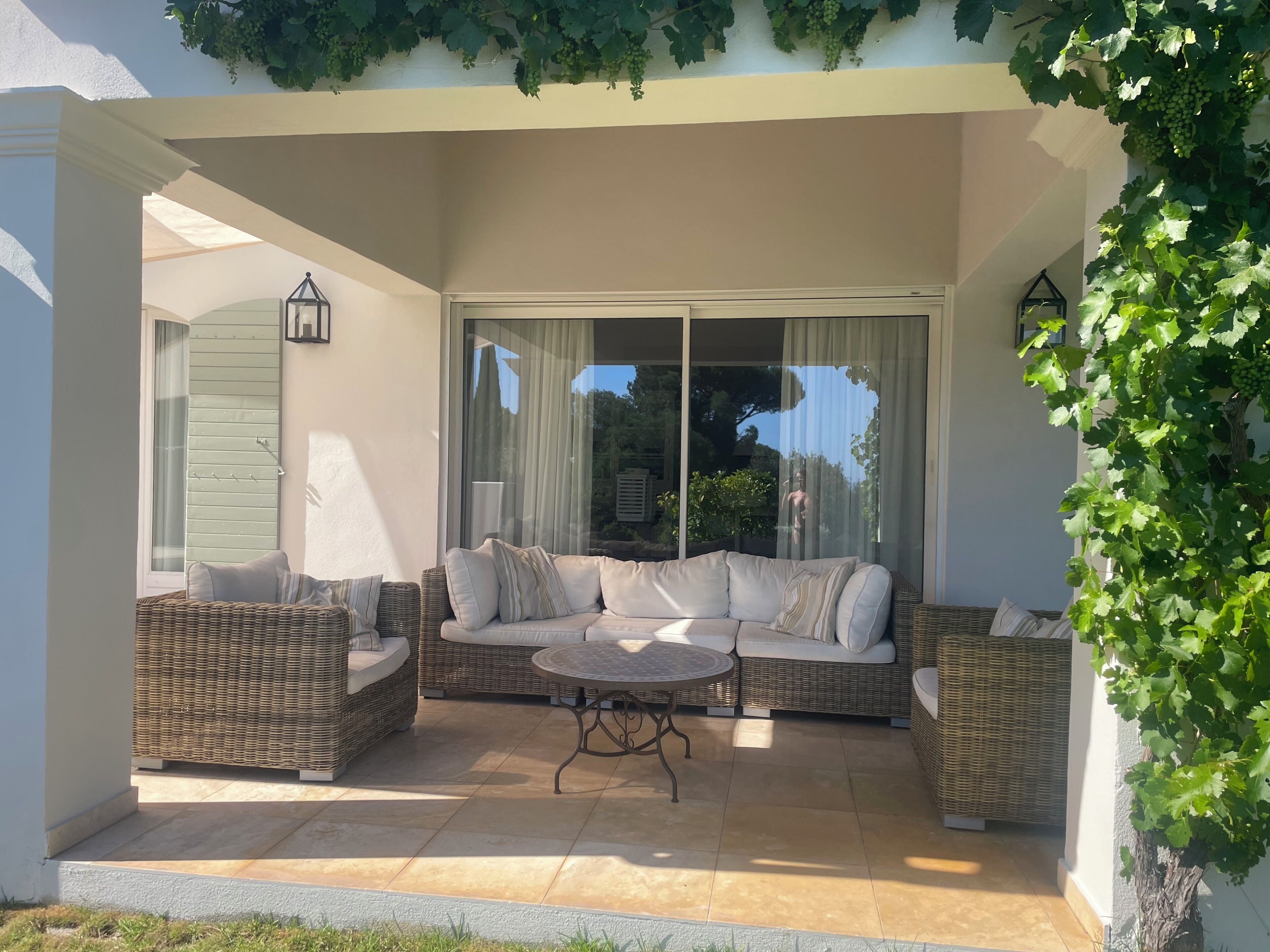 A covered patio with wicker furniture, a round table, and a sliding glass door.