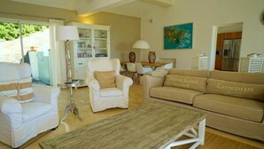 A spacious living room with a white sofa set, a wooden coffee table, and a dining area with a table and chairs. - Côte d'Azur, luxury domestic villa, pool, air conditioning, sea view (La Croix-Valmer)