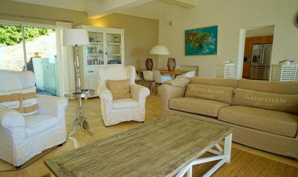 A spacious living room with a white sofa set, a wooden coffee table, and a dining area with a table and chairs. - Côte d'Azur, luxury domestic villa, pool, air conditioning, sea view (La Croix-Valmer)