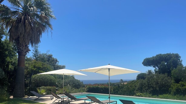 A pool area with lounge chairs and umbrellas, surrounded by greenery and a clear view of the sea. - Côte d'Azur, luxury domestic villa, pool, air conditioning, sea view (La Croix-Valmer)