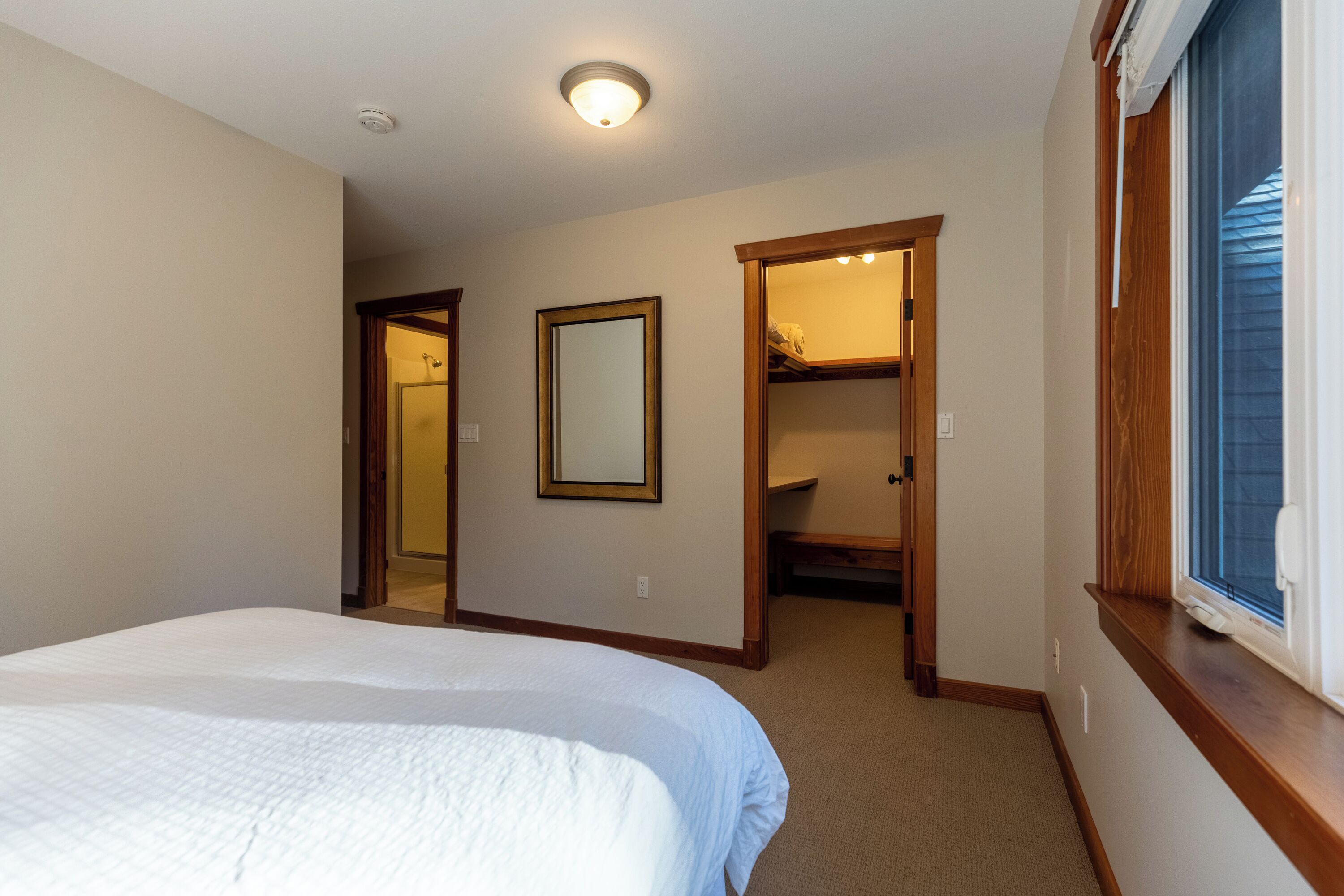A bedroom with a bed, a mirror, and a closet.