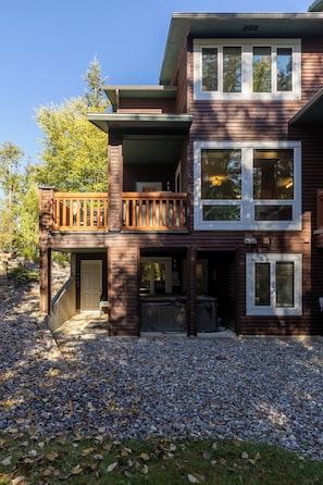 A multi-story house with a balcony, a front door, and a gravel driveway.