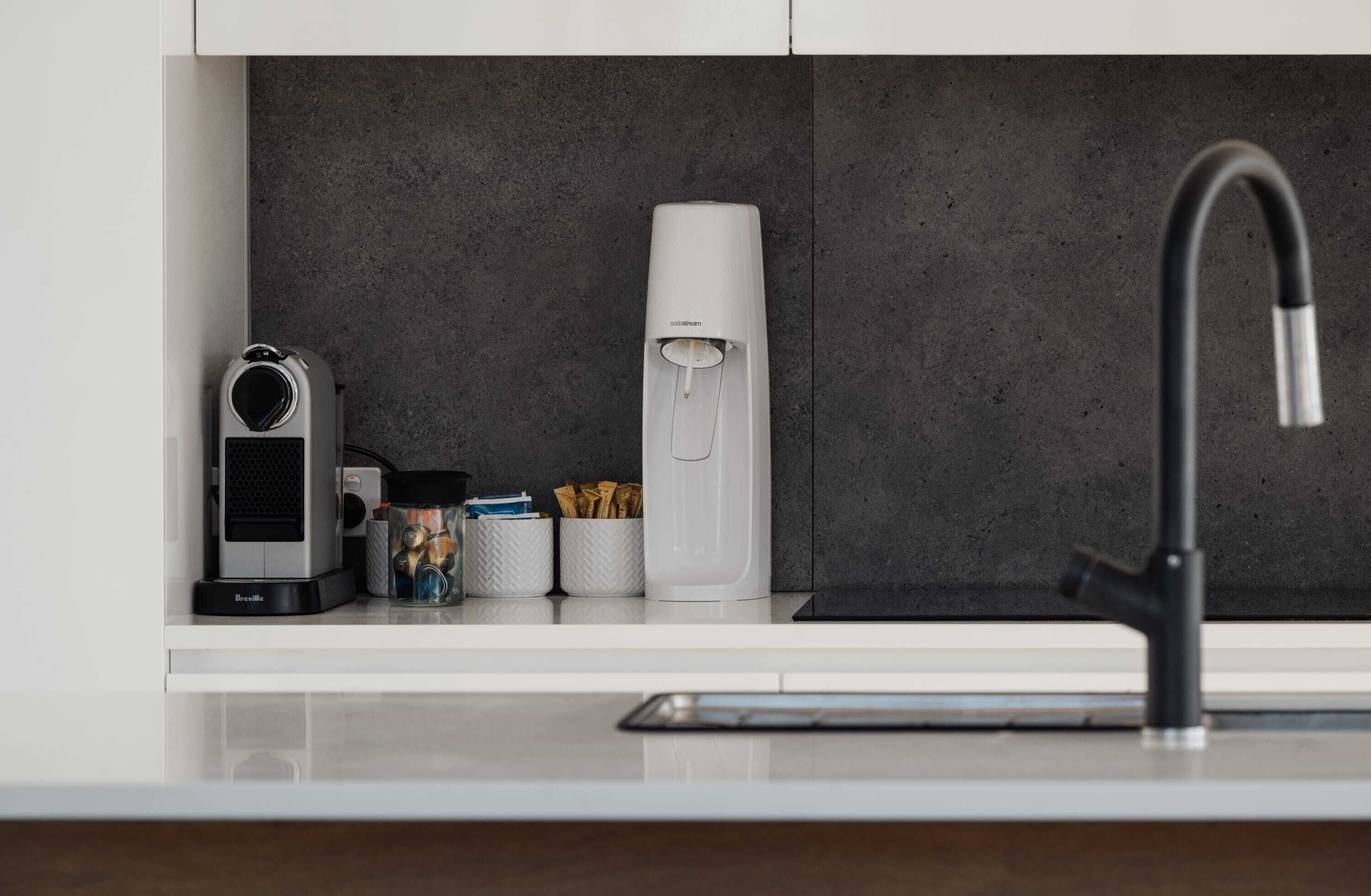 Eine moderne Küche mit einem Breville Kaffeeautomaten, einem Wasserspender und einer Kaffeemühle auf der Arbeitsfläche.