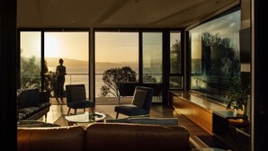 Una sala de estar moderna con un amplio ventanal que da a un balcón con vistas panorámicas.