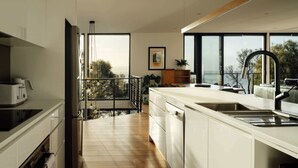 Una cocina moderna con una isla grande, vistas al mar y un balcón con barandilla.