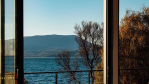 Vista desde una habitación con ventanas amplias que dan a una masa de agua, árboles y colinas distantes.
