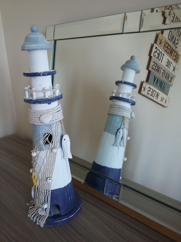 Two lighthouses with ropes and shells, placed on a wooden surface.