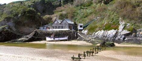 A coastal building with a stone facade, a wooden deck, and a boat docked nearby.