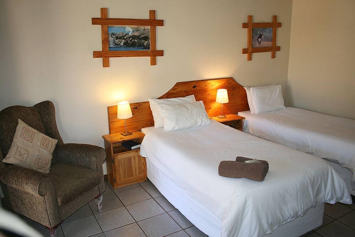 Une chambre d’hôtel avec deux lits, une chaise et des têtes de lit en bois.