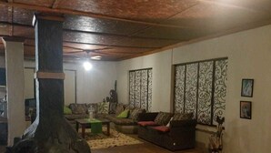 A cozy living room with a large fireplace, comfortable seating, and decorative wall panels.