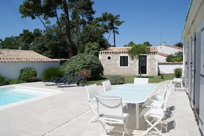 Une terrasse extérieure avec une piscine, des chaises pliantes blanches et une table.