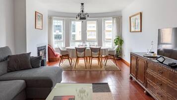 Un salon moderne avec un canapé, une table à manger et des chaises, un téléviseur et une cheminée.