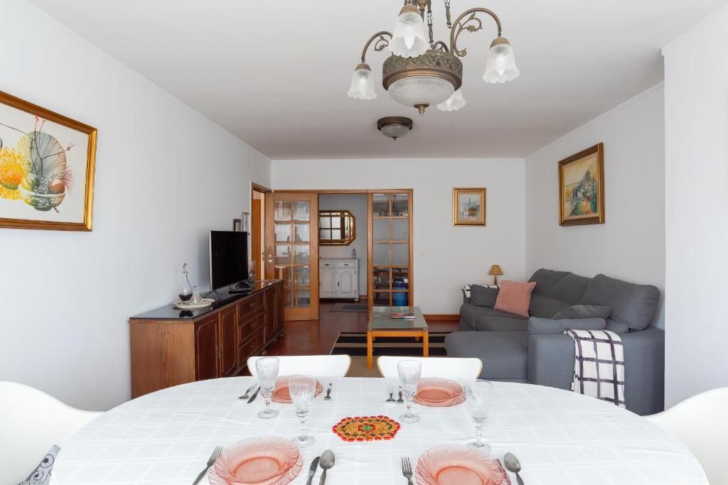 Un coin repas avec une table dressée pour quatre personnes, un canapé et un téléviseur en arrière-plan.