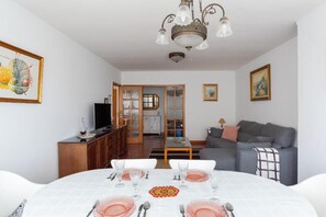 A dining area with a table set for four, a sofa, and a television in the background. - Avenida Apartment by MP (Vila Nova de Gaia)