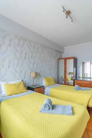 A hotel room with two beds, a nightstand, a lamp, and a mirror. - Avenida Apartment by MP (Vila Nova de Gaia)