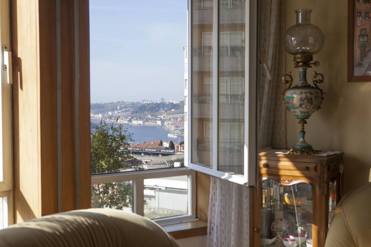 A room with a large window overlooking a cityscape and water.
