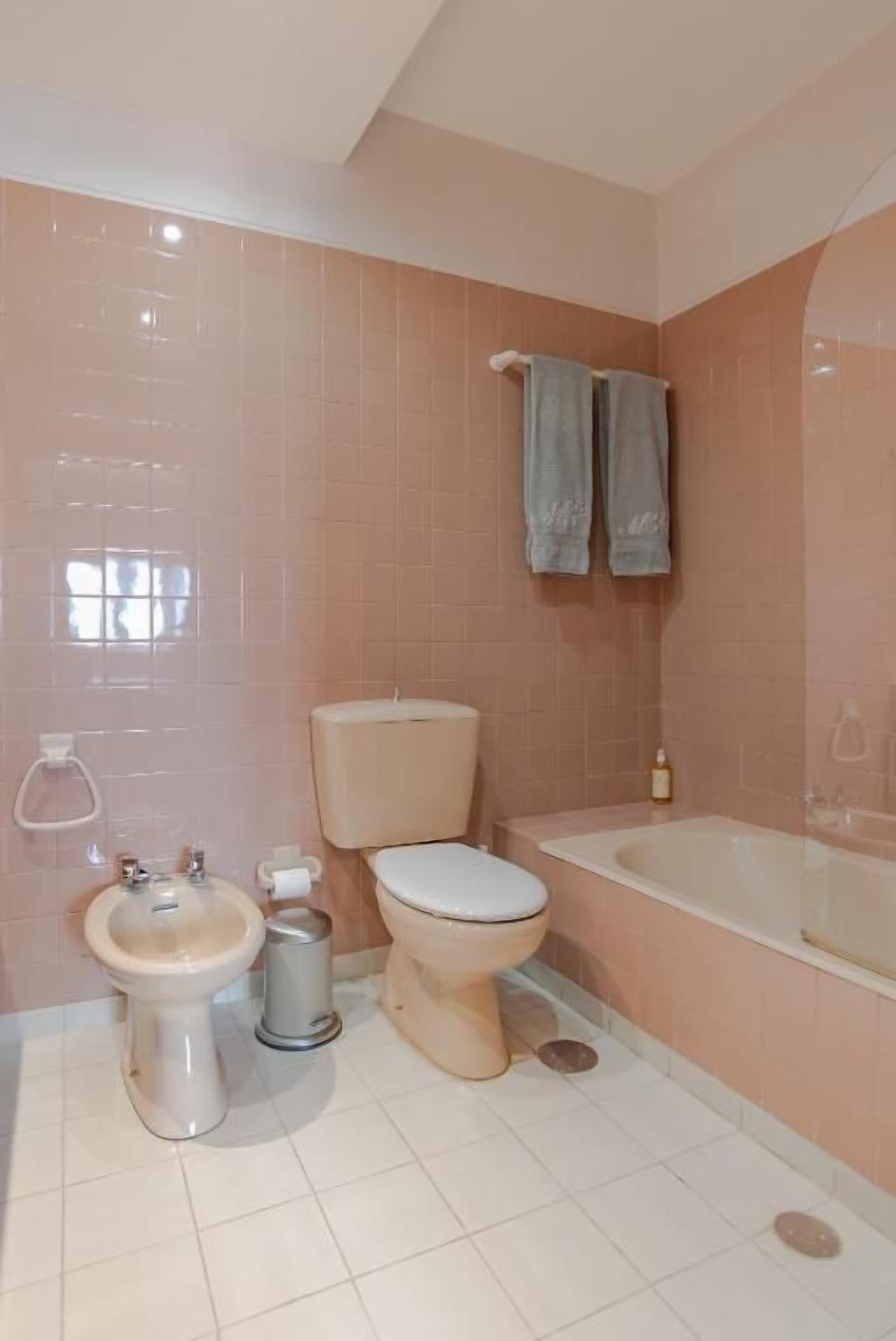 A bathroom with a toilet, bidet, sink, and bathtub.