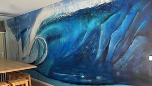 Zona pranzo con un murale raffigurante una scena oceanica blu e un tavolo in legno con sedie.
