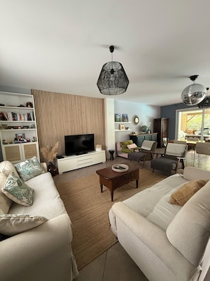 A living room with a television, sofa, coffee table, and decorative items. - ONDRES Villa near beach with pool and spa  (Ondres)
