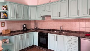 Eine Küche mit hellblauen Schränken, einer Granitabdeckung, einer doppelten Spüle und einem eingebauten Backofen.