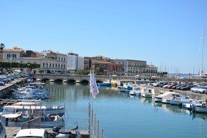 Uma marina com barcos atracados, uma ponte e edifícios ao fundo.