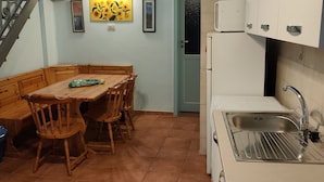 Uma cozinha compacta com área de refeições, escada e porta para outro cômodo.