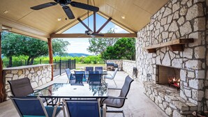 Une terrasse extérieure avec un mur en pierre, une table à plateau de verre et des chaises.