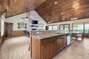 A spacious kitchen with wooden cabinets, granite countertops, and a stone accent wall. - Beautiful Sunset Views, Private Pool & Outdoor Kitchen in Concan, TX (Concan)