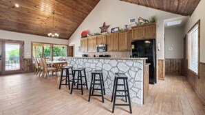Une cuisine spacieuse avec des meubles en bois, un îlot central en pierre et un grand îlot doté de tabourets de bar.