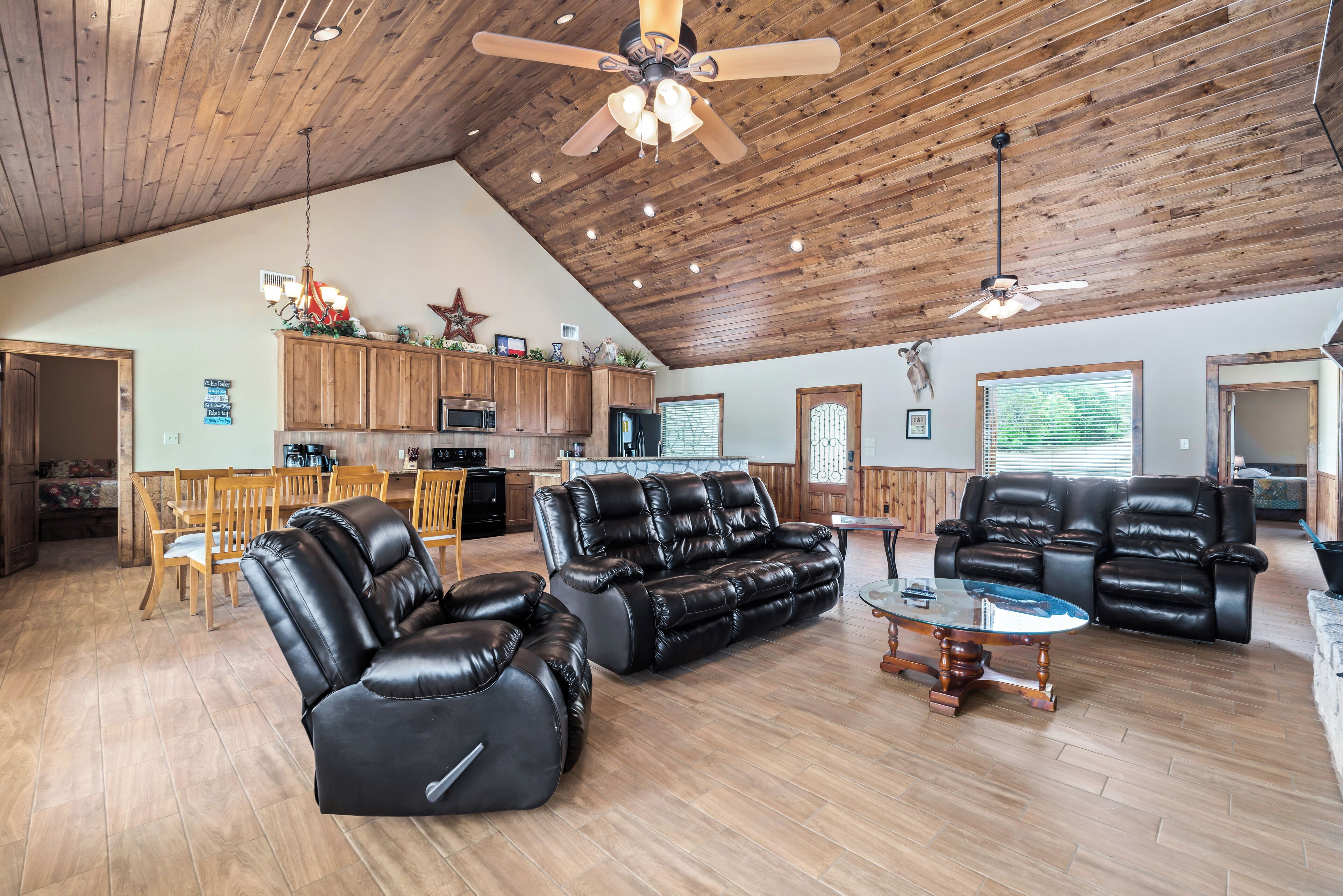 A spacious living area with leather sofas, a dining table, and a kitchen in the background.
