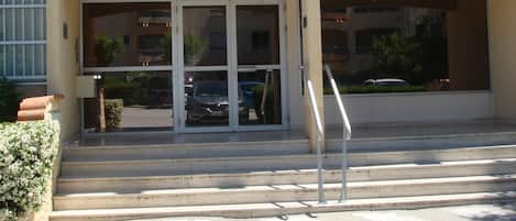 A building with a sign reading "URANUS" at the entrance, featuring a double staircase and a glass door.