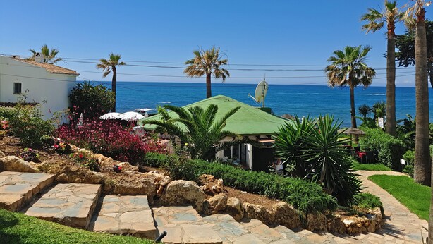 A coastal property with a stone pathway, palm trees, and a view of the sea. - Beachfront apartment with amazing views & newly renovated with WiFi and int. TVs (Mijas)
