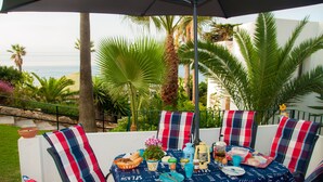 An outdoor dining area with a table set for four, surrounded by chairs with striped cushions. - Beachfront apartment with amazing views & newly renovated with WiFi and int. TVs (Mijas)
