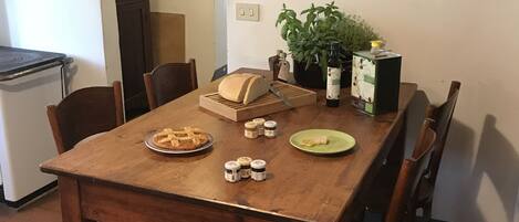 A dining table with a loaf of bread, a plate of waffles, and condiments. There is a potted plant and a bottle of wine on the table.