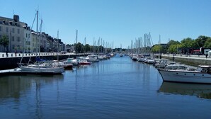 A marina with numerous boats docked along a canal, surrounded by buildings and greenery.