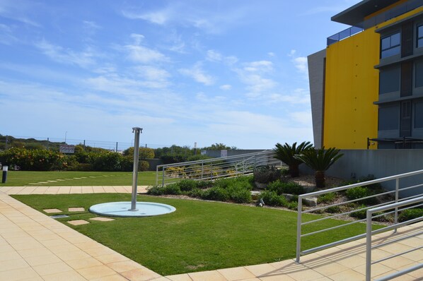 A landscaped outdoor area with a fountain, a staircase, and a building with yellow and grey exterior walls. - Excellent apartment at 50 mtrs. beach with sea view, saltwater pool (Quarteira)