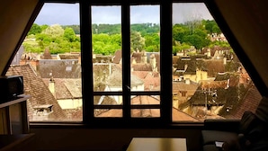 Une pièce dotée d’une grande fenêtre donnant sur un quartier urbain densément bâti, caractérisé par une architecture traditionnelle.