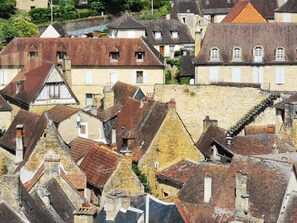 Un ensemble de bâtiments historiques aux styles de toits variés et aux façades en pierre, typiques d’un centre-ville européen.
