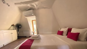 Une chambre à coucher avec un lit, une armoire blanche, un ventilateur et une fenêtre.